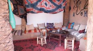 una camera con divano, tavolo e sgabelli di Auberge Tigida a M'Hamid