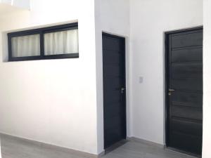 two black doors in a white wall with windows at Sierra Alta Carlos Paz in Villa Carlos Paz +80 photos
