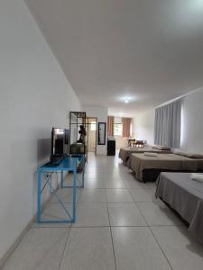 a room with three beds and a blue table in it at Estúdio Charmoso no Centro de Apiaí in Apiaí