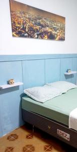 a bed in a room with a painting on the wall at Casa aconchegante perto da praia in Guarujá