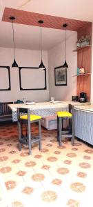 a room with two tables and two yellow benches at Casa aconchegante perto da praia in Guarujá