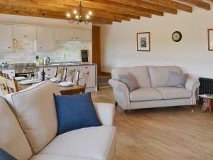 a living room with two couches and a kitchen at The Byres in Greenhaugh