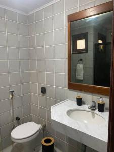 un bagno con un water, un lavandino e uno specchio di Apt 202 a Marechal Deodoro