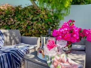 a table with a vase of pink flowers and glasses at Strand Boat House in Cape Town +33 photos