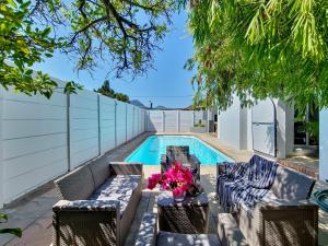 a pool with chairs and a table with flowers at Strand Boat House in Cape Town