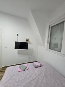 Apartman Divcibare Bela NS 56m2 Lux في ديفشيبار: غرفة نوم بيضاء مع سرير مع منشفتين ورديتين