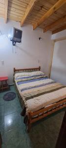 Cama en habitación con TV en la pared en Hospedaje Don Hilario, en Gobernador Gregores