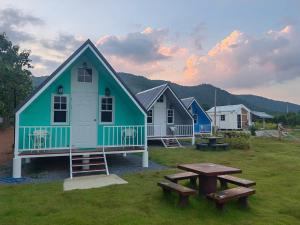 a group of houses with a picnic table and benches at ลุงไซยเดอะแคมป์ in Ban Wang Hin Ngon