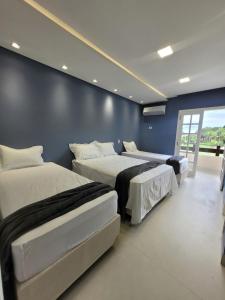 three beds in a room with a blue wall at Condomínio Clube lazer total na Praia da Enseada in Guarujá