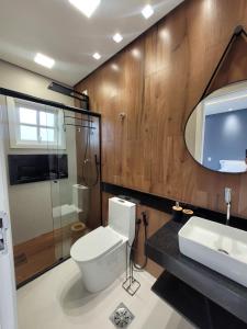 a bathroom with a toilet and a sink and a mirror at Condomínio Clube lazer total na Praia da Enseada in Guarujá