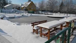 a tennis court covered in snow with two benches at Sportpenzion Pohoda in Pilsen