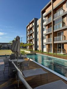 a pool with chairs and an umbrella next to a building at Lindo Apto Águas de Guarajuba in Guarajuba