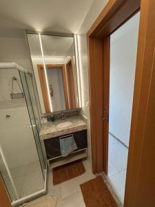 a bathroom with a sink and a mirror at Lindo Apto Águas de Guarajuba in Guarajuba