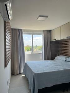 a bedroom with a bed and a large window at Lindo Apto Águas de Guarajuba in Guarajuba