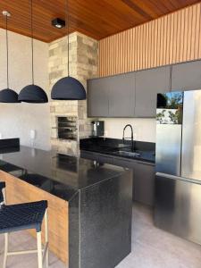 a kitchen with a black counter and a refrigerator at Lindo Apto Águas de Guarajuba in Guarajuba +51 photos
