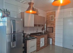 a kitchen with a stainless steel refrigerator and wooden cabinets at Casa de praia natureza in Torres