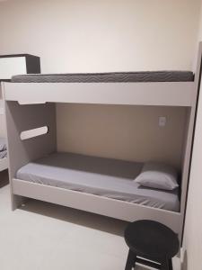 a bunk bed in a room with a stool at Apartamento praia do quilombo Centro - 02 in Penha
