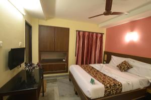 een slaapkamer met een bed en een flatscreen-tv bij Hotel Vijay in Madurai