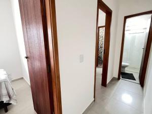 a hallway with a bathroom with a toilet and a mirror at Apt no Santa Mônica próximo ao Pátio Sabiá, UFU in Uberlândia