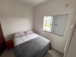 a white bedroom with a bed and a window at Apt no Santa Mônica próximo ao Pátio Sabiá, UFU in Uberlândia