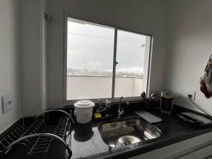 a kitchen counter with a sink and a window at Apt no Santa Mônica próximo ao Pátio Sabiá, UFU in Uberlândia