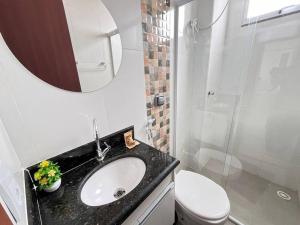 a bathroom with a sink and a toilet and a mirror at Apt no Santa Mônica próximo ao Pátio Sabiá, UFU in Uberlândia