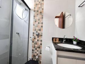 a bathroom with a sink and a shower with a mirror at Apt no Santa Mônica próximo ao Pátio Sabiá, UFU in Uberlândia