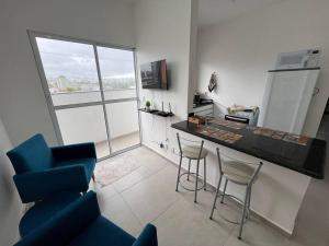 a living room with a kitchen with a counter and chairs at Apt no Santa Mônica próximo ao Pátio Sabiá, UFU in Uberlândia