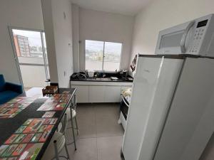a kitchen with a refrigerator and a table and a sink at Apt no Santa Mônica próximo ao Pátio Sabiá, UFU in Uberlândia