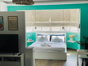 a bedroom with a white bed and a tv at Nimmala - Home Studio at Nimman in Chiang Mai