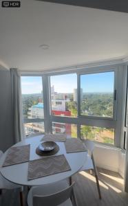 プンタ・デル・エステにあるPiso 16 Punta del Este, Ocean Drive Countryの大きな窓のある部屋にあるテーブルと椅子
