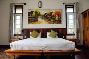 una camera da letto con un letto e un quadro sul muro di Hoi An Holiday Villa a Hoi An Altre 76 foto