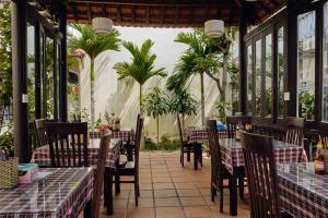 un ristorante con tavoli, sedie e palme di Hoi An Holiday Villa a Hoi An