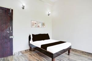 Cama en habitación con paredes blancas y suelo de madera. en Hotel O Oyasis.in, en Nagpur