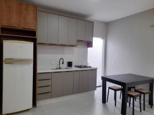a kitchen with a black table and a white refrigerator at Apartamento praia do quilombo Centro - 02 in Penha