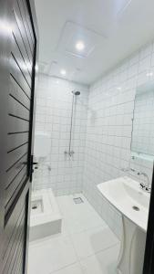 a white tiled bathroom with a sink and a shower at Hotel 11 in Islamabad +29 photos