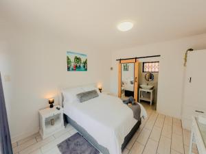 a bedroom with a large white bed in a room at Gaiaqua Guesthouse in Gqeberha