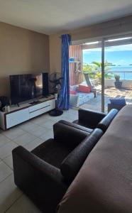 a living room with a couch and a television at L'Horizon in Bora Bora