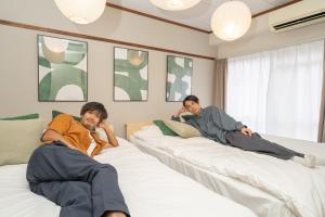 two men laying on beds in a room at Midtown OIMACHI Hub in Tokyo