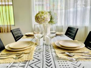 a table with plates and glasses and a vase with flowers at Cascada Apartment 3 Bedrooms 2 Bath in Baños