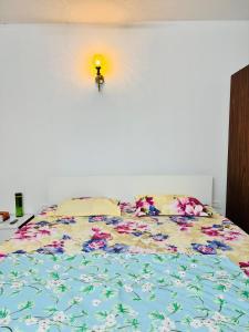 a bed with a colorful comforter and a light on the wall at 6Floor in society Ecity ph2 Near TCS Tech Mahindra in Bengaluru