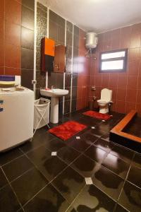 a bathroom with a sink and a toilet and red tiles at The Obour Escape in Obour