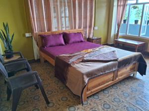a bedroom with a bed with purple sheets and a chair at Room in Kalimpong in Kalimpong