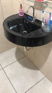 a bathroom sink with a black counter top at Pé na areia in Ilha Comprida +10 photos