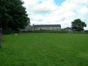 a large grass field with a house in the background at Staden Grange in Buxton
