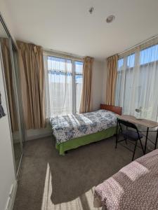 オークランドにあるNewmarket Homestay - Twin Roomのベッド2台とテーブルと窓のある寝室