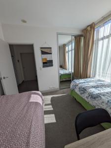 オークランドにあるNewmarket Homestay - Twin Roomのベッドが2つと鏡があるホテルの部屋