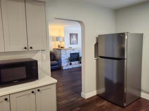 a kitchen with a stainless steel refrigerator and a living room at Harbour Light Motel in Nanaimo