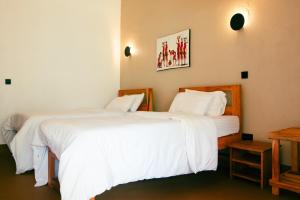 two beds in a hotel room with white sheets at Misitu Eco-Lodge in Karatu
