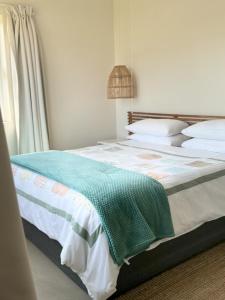 a bedroom with a bed with a green blanket on it at Secrets 2 at Waterkant 7 in Jeffreys Bay